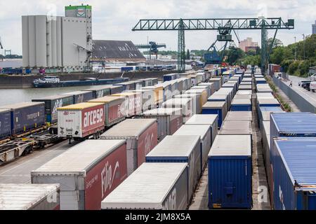 Una gru a portale presso il terminal dei container nel porto del Reno Niehl, i semirimorchi per camion sono pronti per il carico sui treni merci, Colonia, Germania. Porta Foto Stock