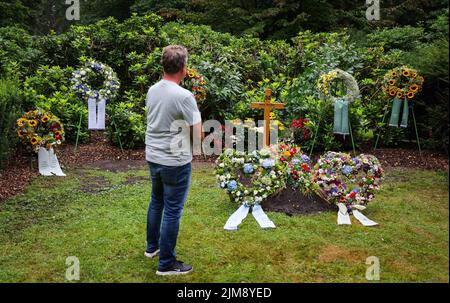 Amburgo, Germania. 05th ago 2022. Un uomo si erge in silenzio ricordo alla tomba della leggenda del calcio Uwe Seeler, che è decorata con corone e fiori. Lo sportivo popolare è stato sepolto il 04 agosto nel più vicino circolo di famiglia al cimitero di Ohlsdorf. Uwe Seeler morì il 21.07.2022 all'età di 85 anni. Credit: Christian Charisius/dpa/Alamy Live News Foto Stock