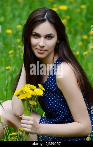 La bella donna nel campo con il tarassaco Foto Stock