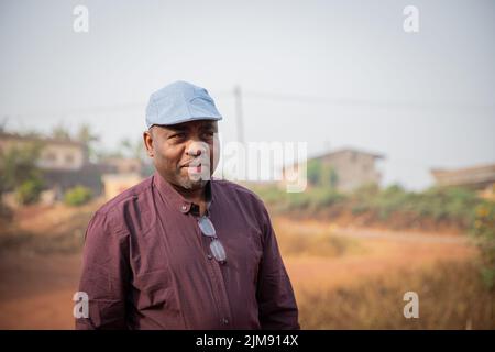 Ritratto di un Signore africano maturo felice che indossa un cappello piatto all'aperto Foto Stock