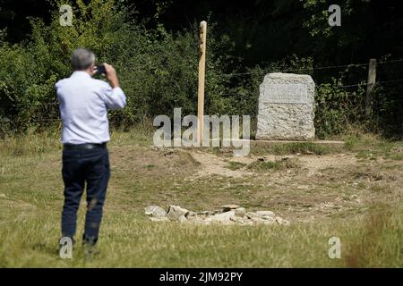 Un uomo fotografa la pietra che segna il posto per la fonte tradizionale del Tamigi conosciuto come Thames Head, un gruppo di sorgenti stagionali vicino al villaggio di Coates nel Cotswolds, Gloucestershire. Le parti in parcheggia dell'Inghilterra stanno affrontando un divieto del tubo di hosepipe in condizioni molto asciutte e davanti ad un'altra ondata di calore prevista. Data foto: Venerdì 5 agosto 2022. Foto Stock