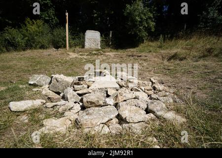 La pietra che segna il posto per la fonte tradizionale del Tamigi conosciuto come Thames Head, un gruppo di sorgenti stagionali vicino al villaggio di Coates nel Cotswolds, Gloucestershire. Le parti in parcheggia dell'Inghilterra stanno affrontando un divieto del tubo di hosepipe in condizioni molto asciutte e davanti ad un'altra ondata di calore prevista. Data foto: Venerdì 5 agosto 2022. Foto Stock