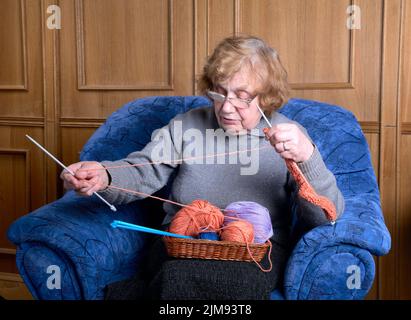 La nonna si siede in una poltrona e si inginocchierà Foto Stock