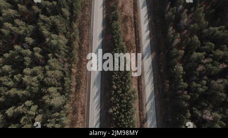 Strada autostradale tra la foresta profonda in Ural, Russia. Bellissimo paesaggio naturale autunnale durante il giorno. Vista aerea da un drone Foto Stock