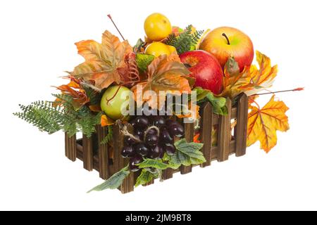 Composizione dalla Frutta artificiale e foglie di autunno in cassetta di legno isolato su sfondo bianco. Foto Stock