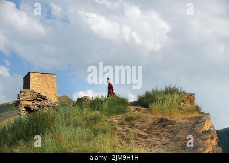 Dagestan, Russia - 21 luglio, 2022: L'uomo locale nella tradizione nazionale vestire rimane contro la torre di battaglia nel villaggio di Goor Foto Stock