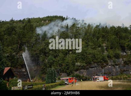 Oybin, Germania. 05th ago 2022. I vigili del fuoco spengono un incendio nella foresta da un veicolo. Un incendio nella foresta è scoppiato nella località nel distretto di Görlitz. I vigili del fuoco non possono arrivare alla fonte del fuoco al momento. Il terreno è altrettanto imperdibile e roccioso come nel Parco Nazionale della Svizzera sassone. Credit: Christian Essler/Xcitepress/dpa/Alamy Live News Foto Stock