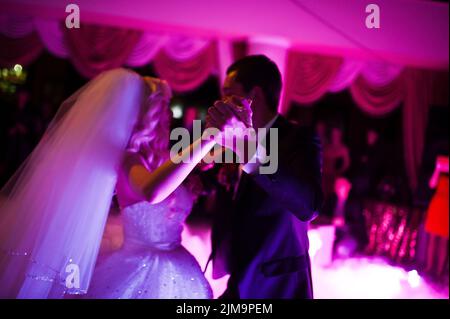 Incredibile primo ballo di nozze di sposi novelli a bassa luce rosa e fumo pesante Foto Stock