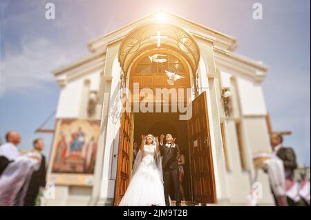 Coppia di mani rilasciando colombe bianche di sposi durante il tramonto Foto Stock