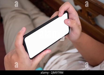 Primo piano di un uomo che utilizza un telefono cellulare con uno schermo vuoto a casa. Foto Stock
