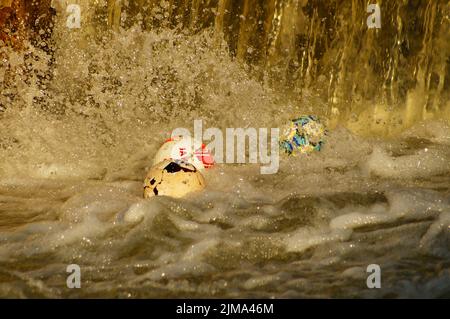 Le palline sono intrappolate sotto uno stramazzo sul fiume Nidda a Francoforte. Driftwood causa un impressionante spruzzo. I pericoli di uno stramazzo sono sottovalutati. Foto Stock