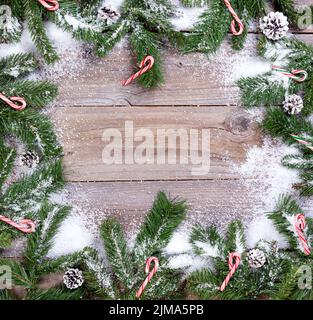 Rami di abete innevati e canne caramelle su tavole rustiche di legno Foto Stock