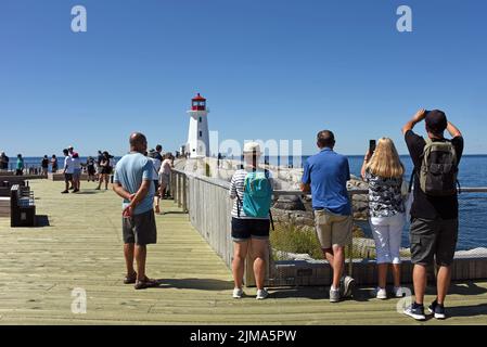 Peggy’s Cove, Canada - 31 luglio 2022: La gente guarda il famoso faro di Peggy’s Cove. Una piattaforma di osservazione in legno è stata installata nel 2021 per dare peopl Foto Stock