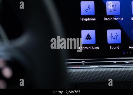 L'icona Google Android Auto è visualizzata in blu sullo schermo di una nuova auto di lusso. Foto Stock