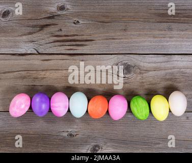 Uova colorate per la vacanza di Pasqua formando bordo inferiore su legno rustico Foto Stock