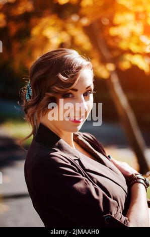 Ritratto di ragazza intelligente con un vecchio stile acconciatura outdoor in cappotto marrone in autunno. Foto Stock