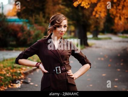 Ritratto di ragazza intelligente con un vecchio stile acconciatura outdoor in cappotto marrone in autunno. Foto Stock