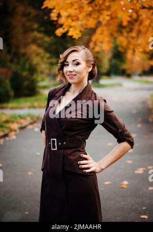 Ritratto di ragazza intelligente con un vecchio stile acconciatura outdoor in cappotto marrone in autunno. Foto Stock