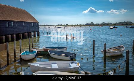 Una coppia su un galleggiante di paddleboard vicino al Bosham Sailing Club Boathouse a Bosham, West Sussex, Regno Unito. Foto Stock