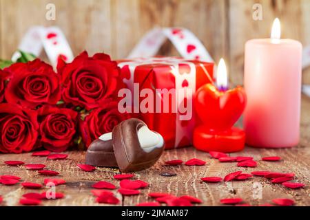 Praline di cioccolato nella parte anteriore del bouquet di rose rosse Foto Stock