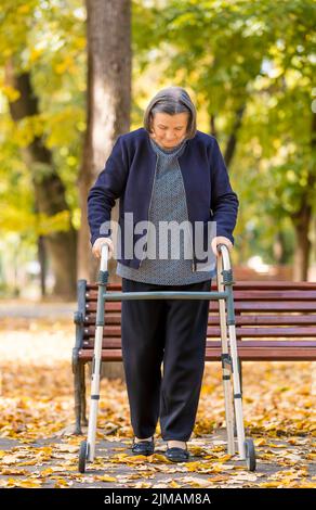 Donna con walker passeggiate all'aperto Foto Stock