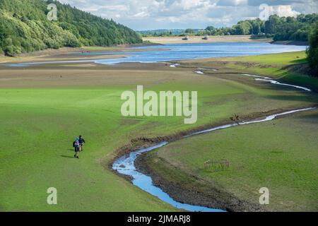 North Yorkshire, Regno Unito. 5th agosto, 2022. Gli escursionisti camminano attraverso il bacino vuoto e asciutto del lago artificiale di Lindley Wood. Il lago artificiale Lindley Wood, utilizzato dall'acqua dello Yorkshire per fornire acqua potabile a Leeds e alle aree circostanti, è quasi vuoto e asciutto. Foto Stock