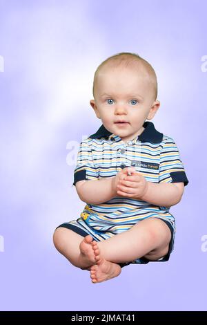 Bambino di 10 mesi su uno sfondo viola Foto Stock