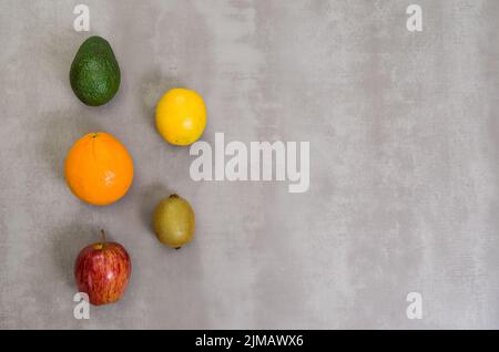 Grande concetto di mangiare sano, vari frutti su sfondo grigio, in cemento lucidato. Arancione, mela, kiwi, limone. Foto Stock