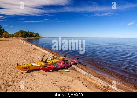 Kayak gialli e rossi si sono tirati sulla spiaggia sabbiosa sulla riva sud del lago Great Slave vicino al fiume Hay nei territori nordoccidentali del Canada. Foto Stock