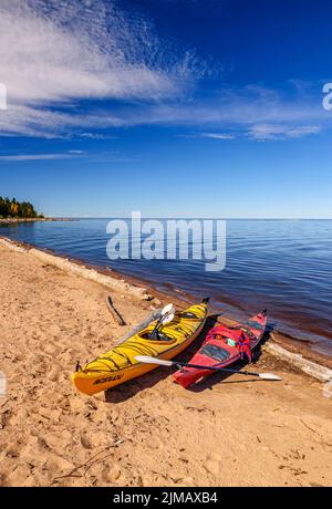 Kayak gialli e rossi si sono tirati sulla spiaggia sabbiosa sulla riva sud del lago Great Slave vicino al fiume Hay nei territori nordoccidentali del Canada. Foto Stock