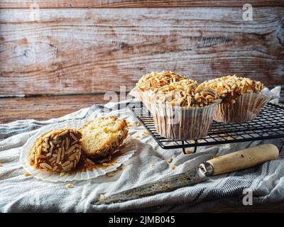 Muffin appena fuori dal forno messo su una griglia di raffreddamento, Cucillo per tagliarlo. Fondo in legno. Capriccio gastronomico. Foto Stock