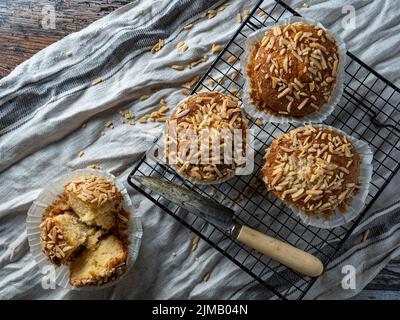 Muffin appena fuori dal forno messo su una griglia di raffreddamento, Cucillo per tagliarlo. Fondo in legno. Capriccio gastronomico. Foto Stock