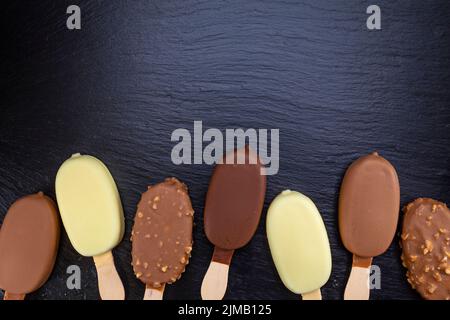Gelato sul bastone ricoperto di cioccolato sul nero Foto Stock