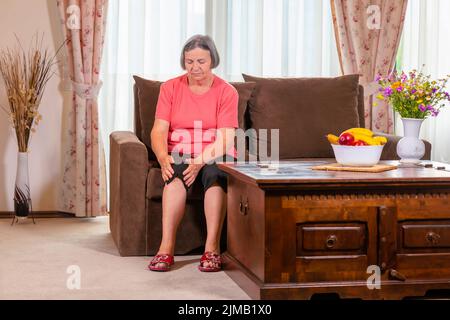 Donna anziana che soffrono di dolore in ginocchio a home Foto Stock