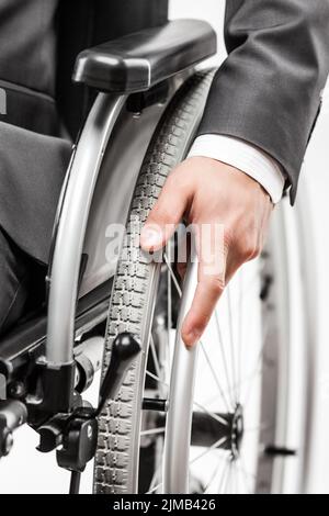 Uomo d'affari non valido o disabile in tuta nera sedia a rotelle seduta Foto Stock