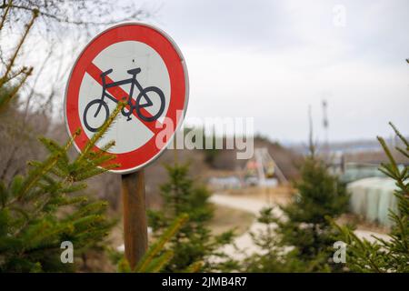 Una messa a fuoco selettiva di un segno No Cycling con alberi e cielo sfondo Foto Stock