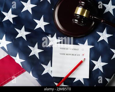 Sulla bandiera americana di Stato c'è un gavel di legno di un giudice, un pezzo di carta con una chiamata a votare per i democratici o repubblicani, una matita rossa. An basso Foto Stock