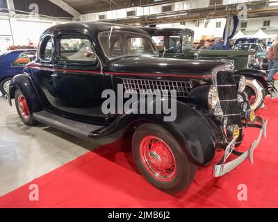 Ripresa di un vecchio coupé nero 1935 Ford V8 Model 48 a cinque finestre in una sala espositiva. Spettacolo di auto classica. Foto Stock