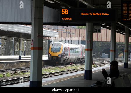 Una foto di un treno CrossCountry in partenza dalla stazione ferroviaria con binario e passeggero in primo piano, a Sheffield, South Yorkshire, Inghilterra Foto Stock