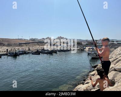 Due bambini che pescano in un piccolo porto Foto Stock