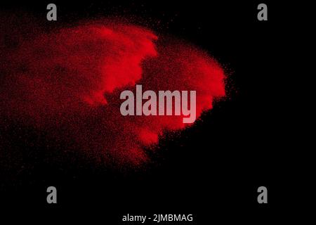 Colore rosso esplosione di polvere su sfondo nero.bloccare il movimento di rosso le particelle di polvere schizzi. Foto Stock