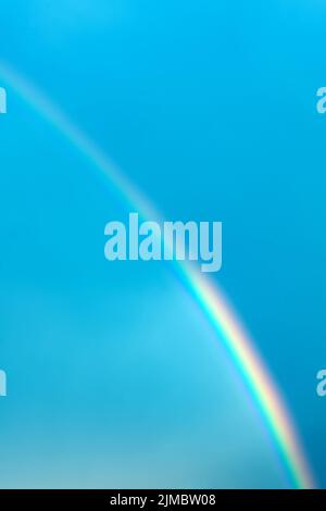 Arcobaleno multicolore sullo sfondo del cielo blu. Foto verticale. Foto Stock