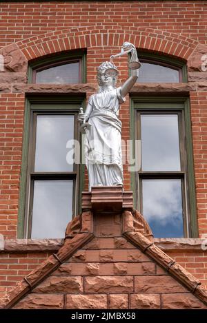 Statua di Lady Justice, non cieca, dipinta d'argento, sulla facciata in mattoni del tribunale della contea di Pitkin, Aspen, Colorado. Foto Stock