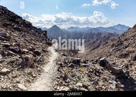 Wadi Shawka stretto sentiero escursionistico in roccia calcarea Hajar Mountains, Emirati Arabi Uniti, con catene montuose sullo sfondo. Foto Stock