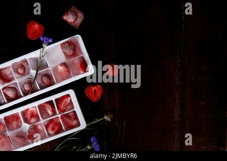 Ghiaccio di fragola nelle forme. Preparazione del ghiaccio estivo per cocktail party, gelati e dessert. Freschezza. Spazio di copia. Foto Stock