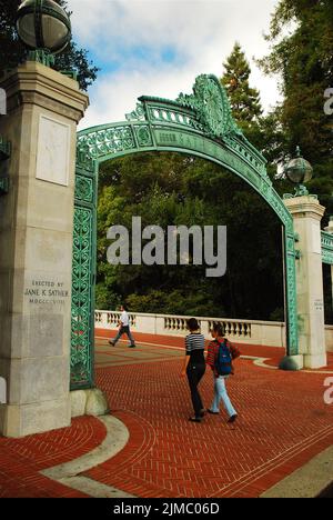 Due studenti universitari camminano attraverso la storica Sather Gates che conduce al campus della University of California Berkeley (Cal) nella Bay Area Foto Stock