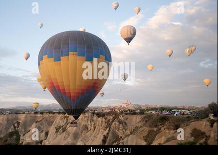 29 giugno 2022, Turchia, Göreme: Palloncini ad aria calda che volano all'alba di fronte ad un altopiano di roccia. Foto: Sebastian Kahnert/dpa Foto Stock