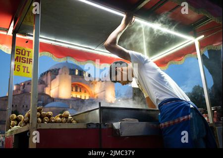 Istanbul, Turchia. 01st luglio 2022. Un uomo vende mais sulla pannocchia di fronte alla chiesa di Santa Sofia. Credit: Sebastian Kahnert/dpa/Alamy Live News Foto Stock