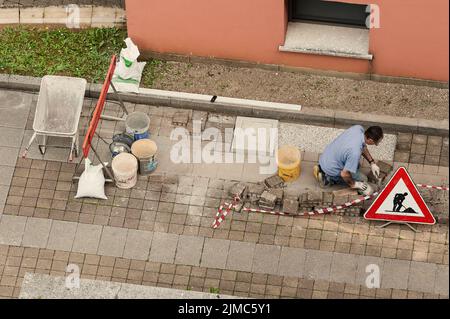 Muratore al lavoro la posa di blocchi di pietra. Foto Stock