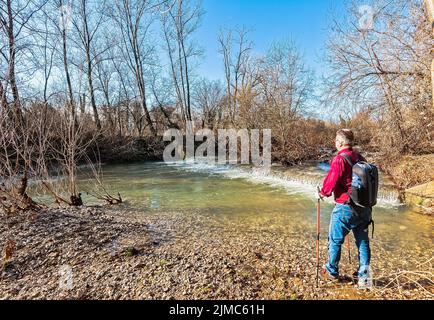 Escursionista di circa 60 anni, sulla riva del torrente. Foto Stock